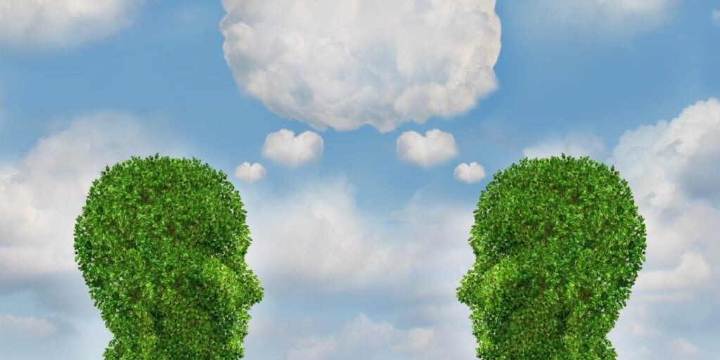 Growing network communication with a group of two trees shaped as a human head with a blank word bubble made of clouds as a business concept of team growth sending a message with cloud technology.